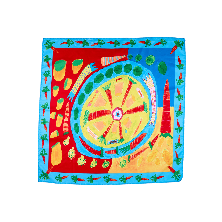 Veggie Christmas Dinner. A square, fabric knot wrap with a blue, carrot-filled border. The centre depicts an illustrated image of a dinner plate with vegetables. It is surrounded by crackers and vegetables on prime colours.