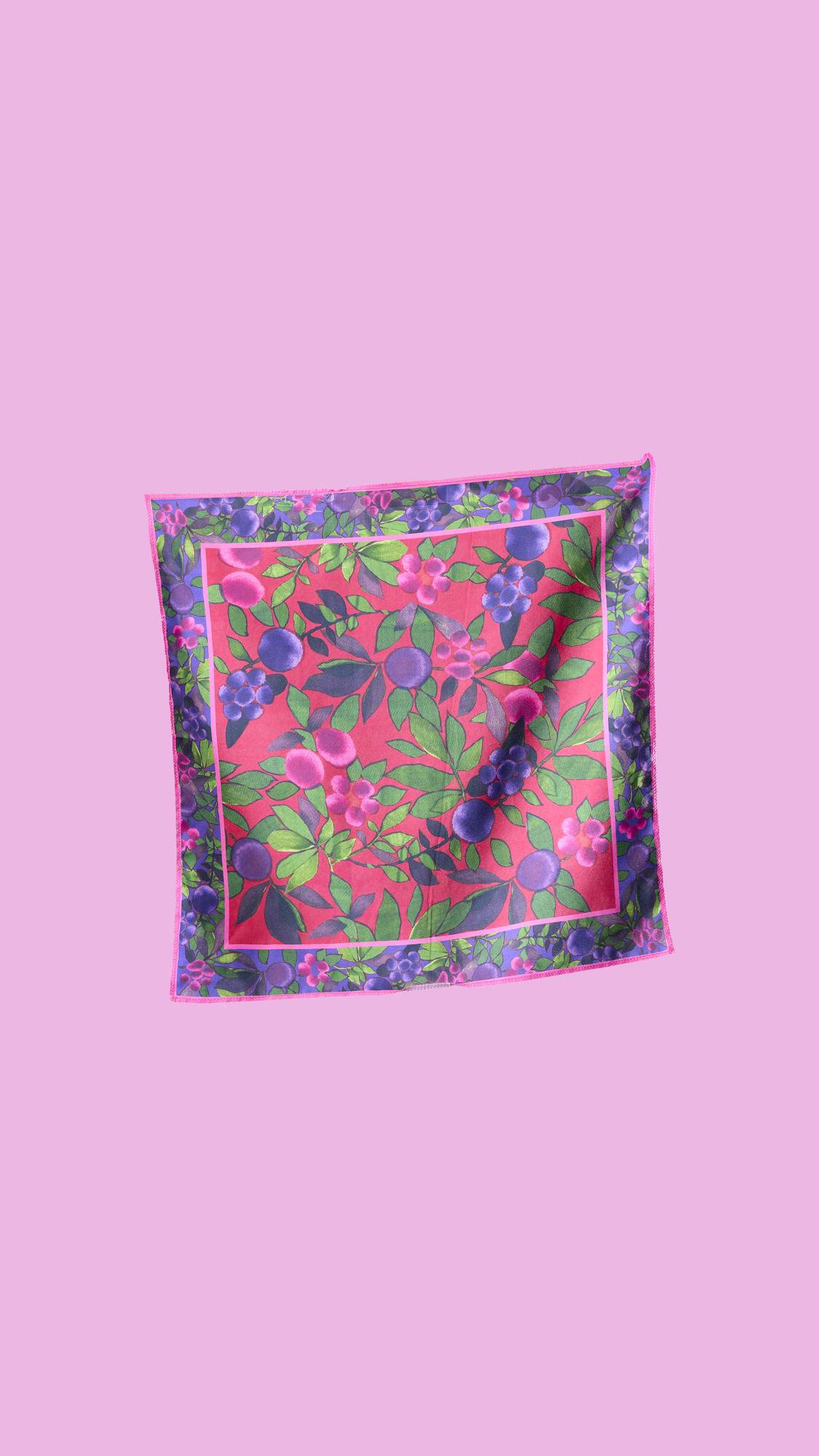 A colorful, reusable Lush "Winter Berries" Knot Wrap. The square fabric features a vibrant pattern of purple and pink berries with green leaves on a fuchsia background and a purple border.