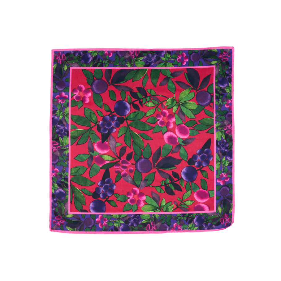 Winter Berries. A square, fabric knot wrap with a colorful, festive design with a red base and green leaves, purple berries, and pink flowers. There is a decorative border with a purple base and the same festive design.