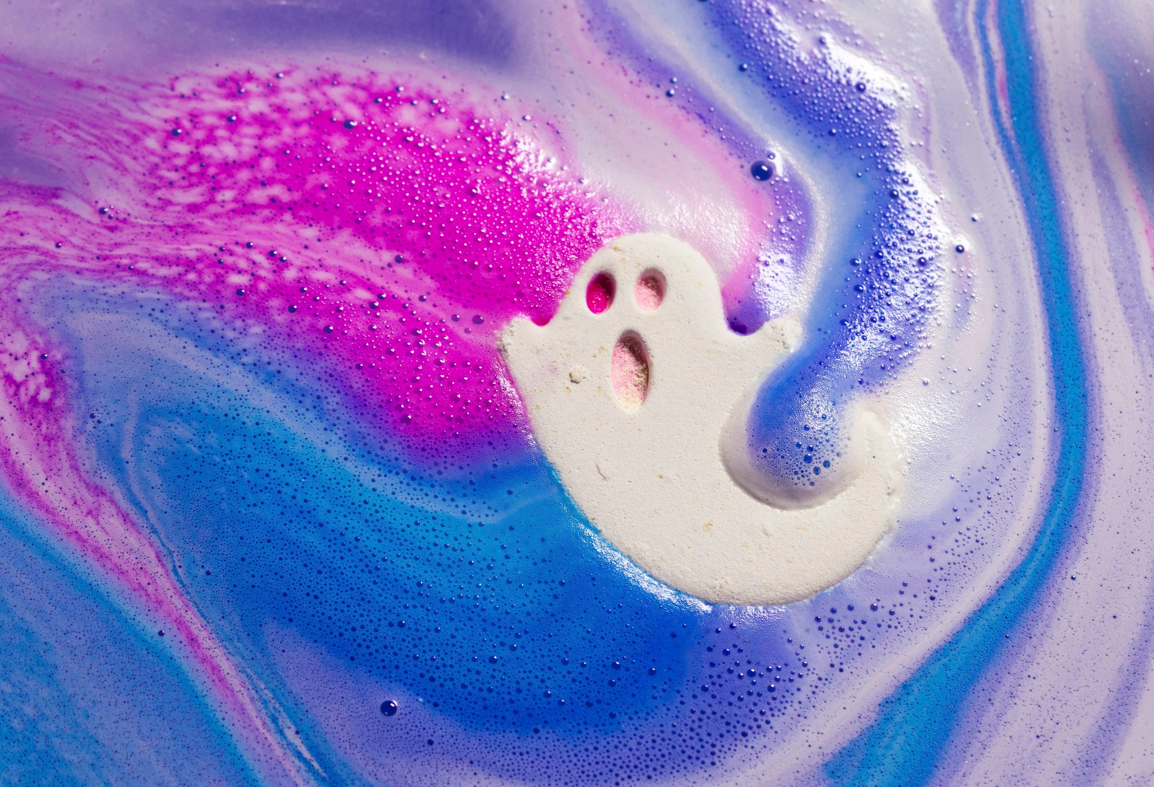 Ghostie bath bomb slowly fizzes away revealing a layer of foamy swirls of pink, purple and blue.
