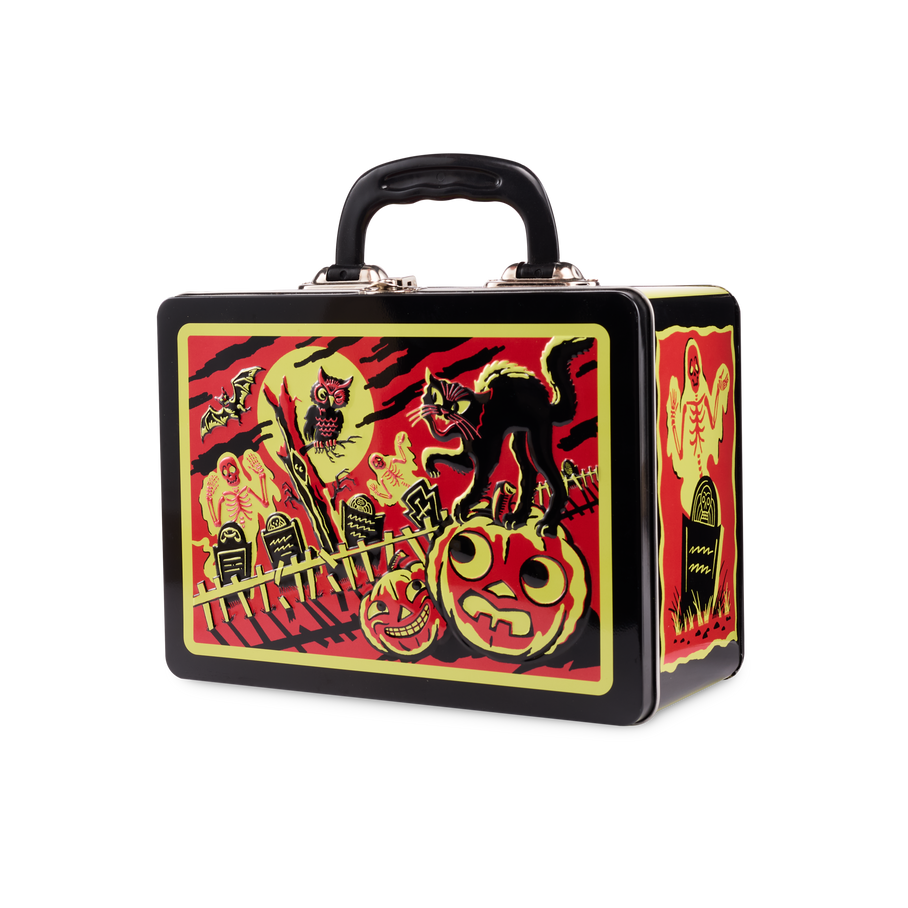 The image shows a black, lunchbox-style metal box with a handle. The front features a red, black and yellow illustration of a black cat on a pumpkin, a ghost, skeleton, and an owl in a classic Halloween graveyard theme.