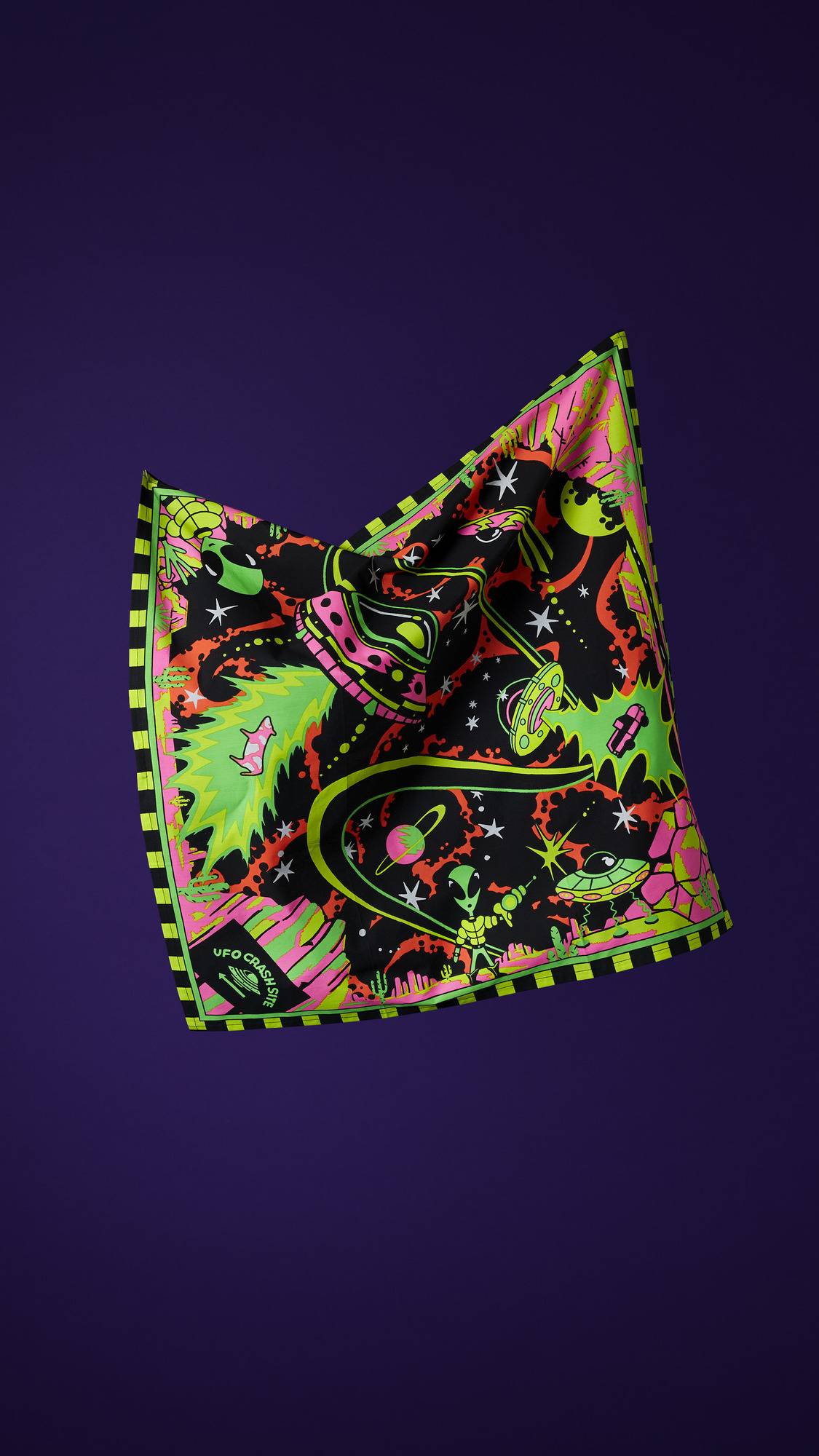 The image shows the square, multicoloured "Nice Planet, I'll Take It" fabric knot wrap with a sci-fi design. It is suspended against a purple background, showcasing UFOs, aliens, and stars in neon colours, with a striped border.