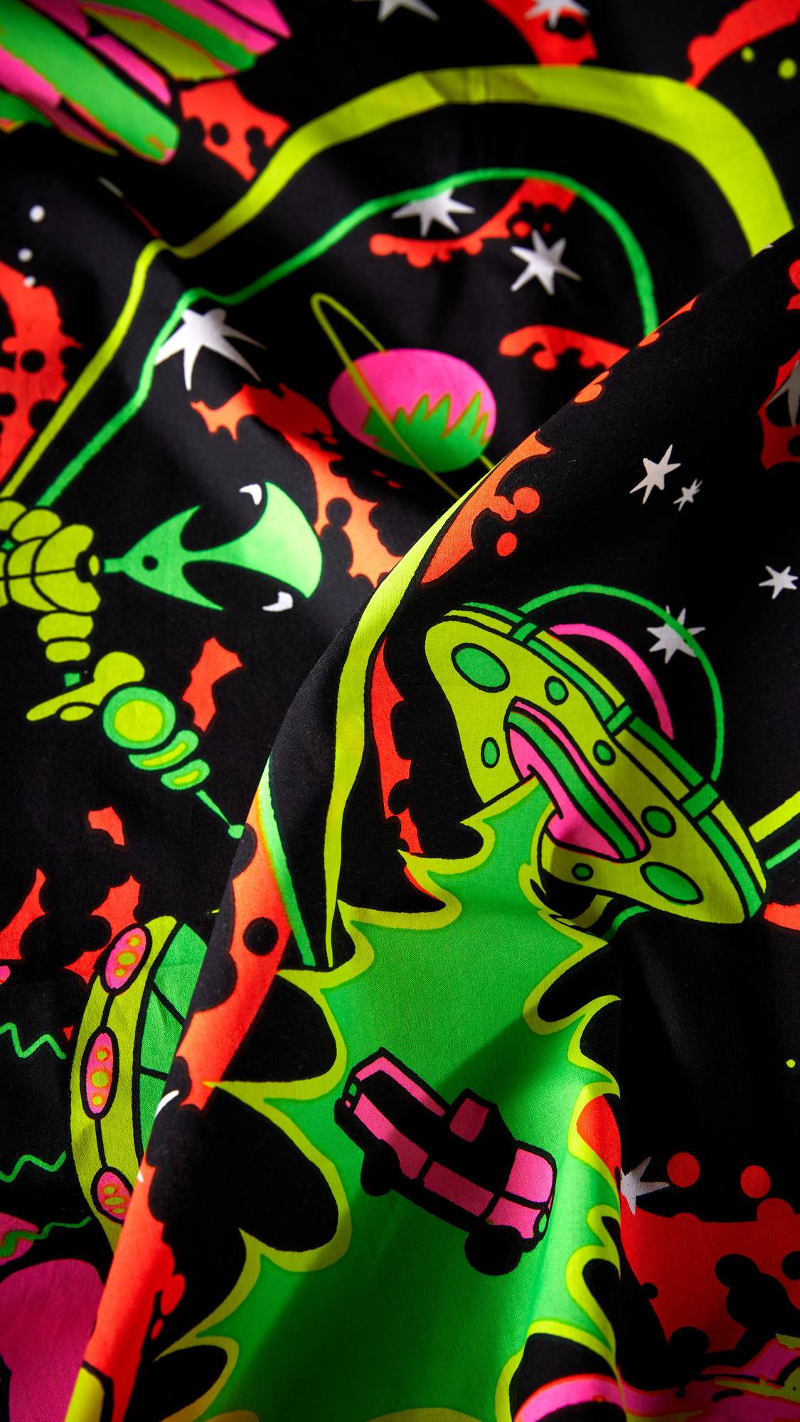 The image shows a close-up of the 'Nice Planet, I'll Take It' knot wrap. The vibrant, multi-coloured fabric is folded, showcasing a psychedelic pattern with UFOs, aliens, planets, and stars.