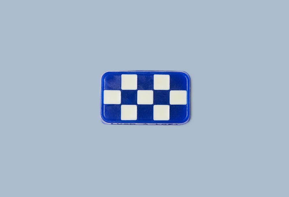 Checked In, a rectangular soap with a white and blue checkered pattern on a light blue background.