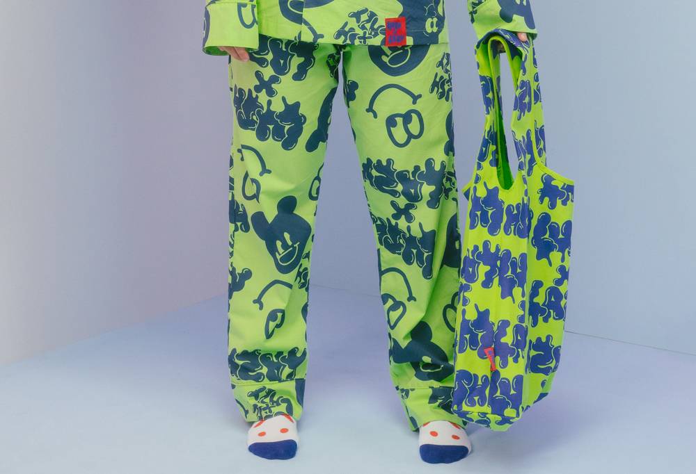 Pyjamas trousers, worn by a model show is wearing the full set and some socks. The model holds the lush x Lazy carrier bag.