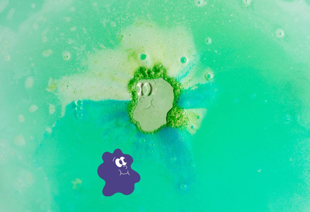 Wash Buddys' smiling face is only just visible as the bath bomb melts and fizzes away into pastel light and dark green waters.