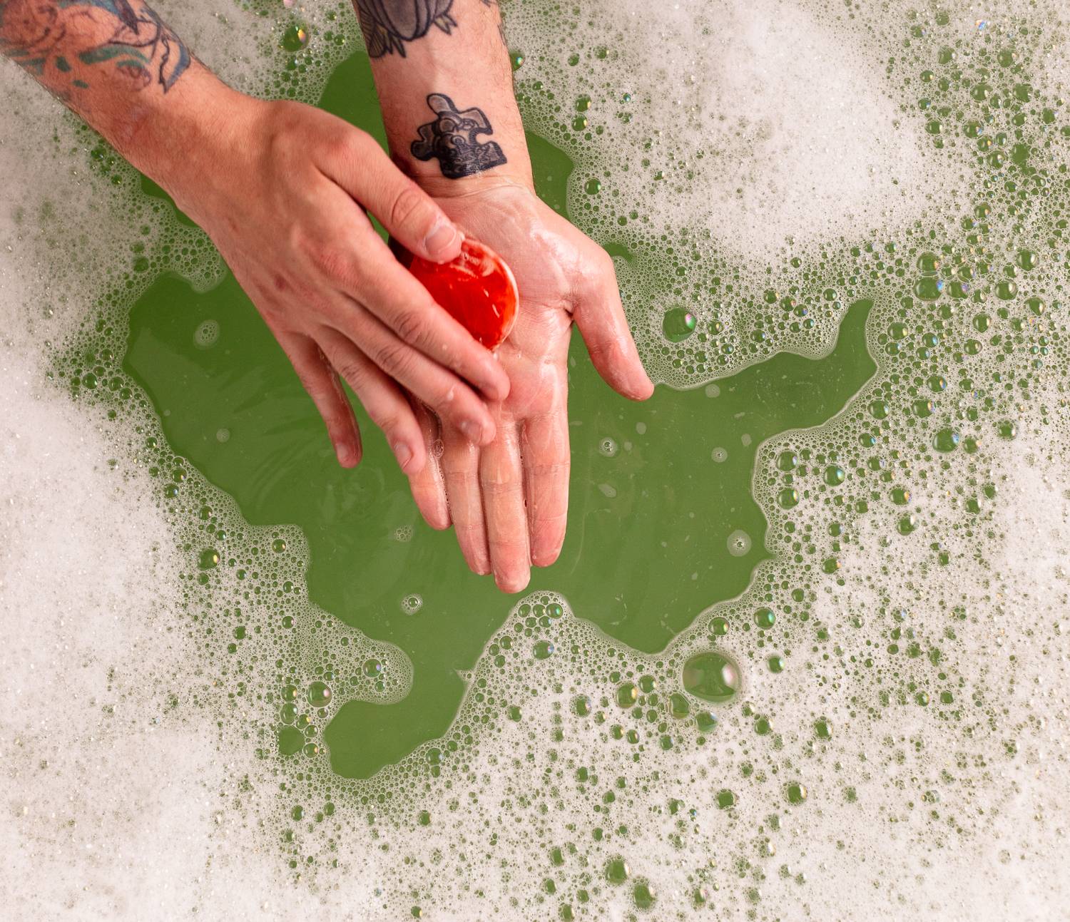 Image shows the model using the tomato-shaped soap in the bath water surrounded by bubbles.