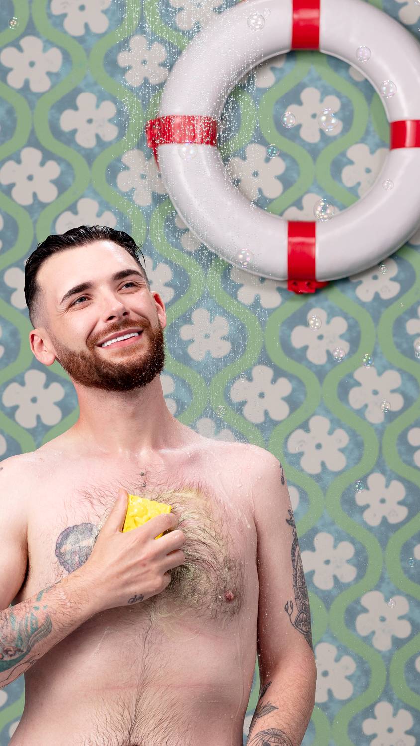 Model is seen in the shower, smiling under running water as they use the Spongebob soap on their chest.