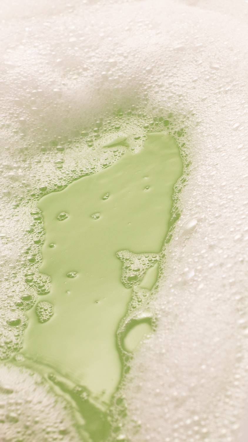 Image shows a thick blanket of bubbles with a hint of shimmery green water below.