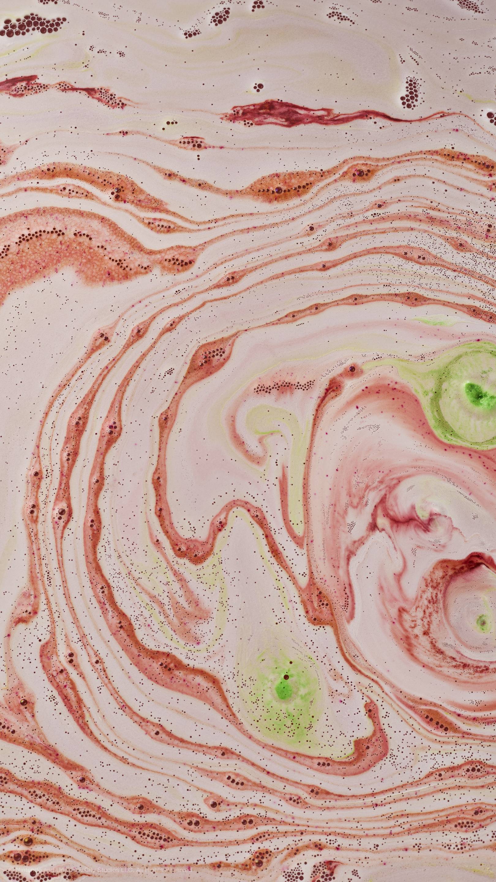 Top-down view of bathwater with swirling patterns of light pink, vibrant red, and lime green foam.