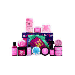A Lush Snow Fairy Magic gift box tied with a mint-green ribbon, arranged with twelve Snow Fairy products, including shower gel, body lotion, body spray, candle, dusting powder, bath bombs, and body care items