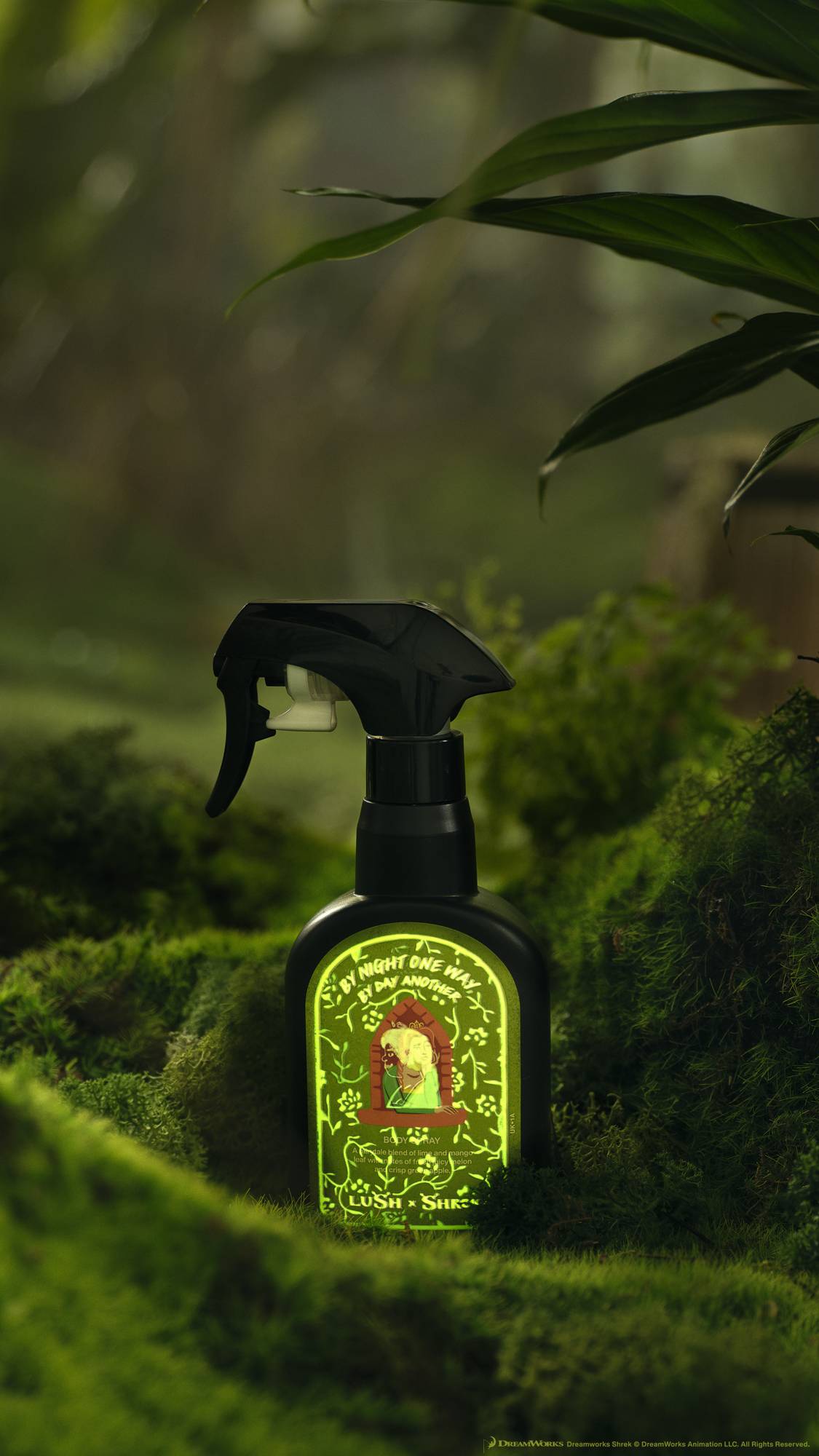 The body spray bottle is sitting on a fluffy, mossy ground with leaves overhead. The label seems to be shifting revealing some glow-in-the-dark markings. 