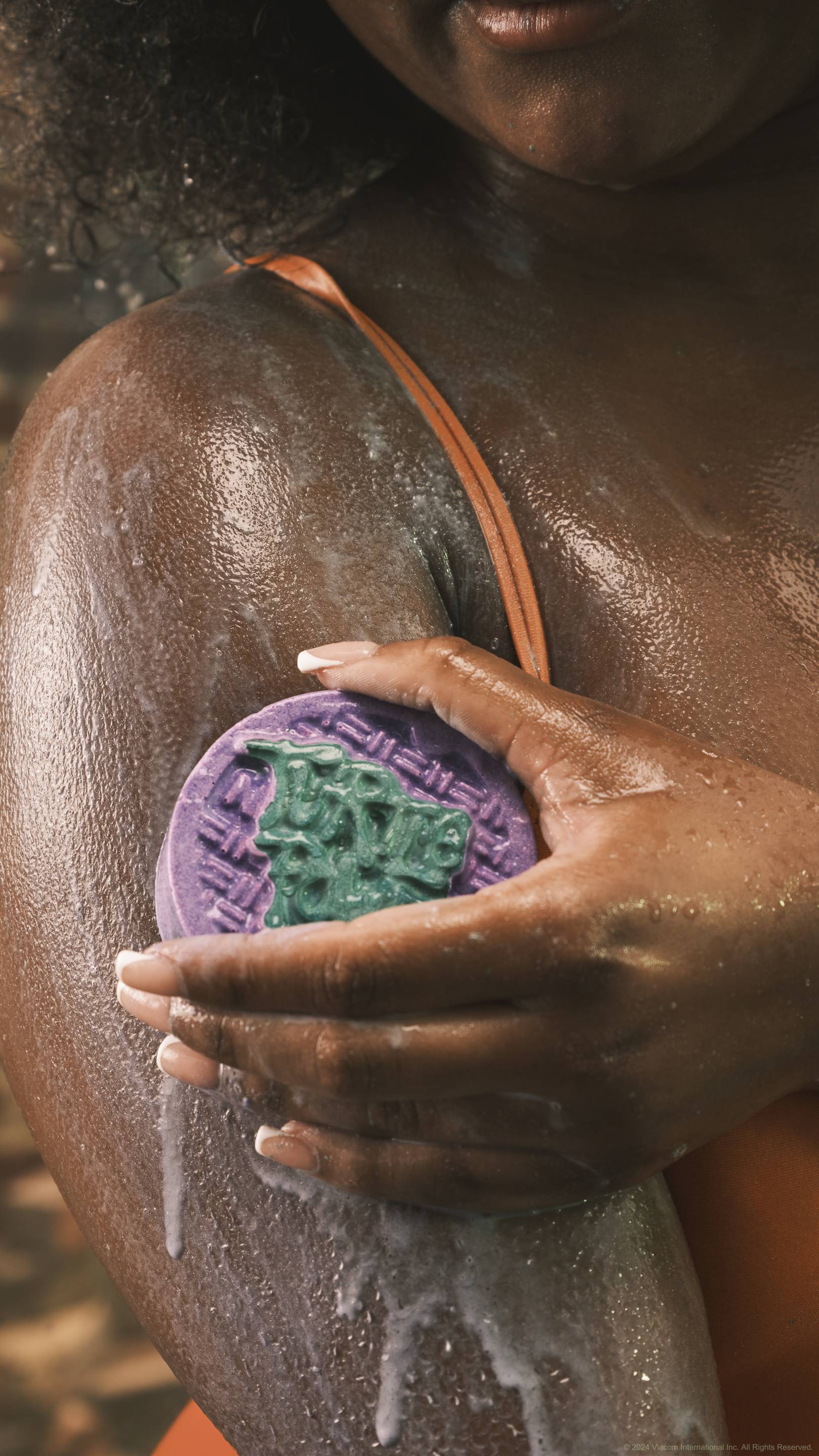 A close-up shot of the model's shoulder which they are lathering up in thick suds with the Turtle Power solid body scrub creating a soft, creamy lacquer. 