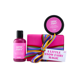 A Lush A Little Snow Fairy Magic gift set wrapped in bright pink with a striped ribbon, flanked by a bottle of pink Snow Fairy shower gel and a tub of Snow Fairy body lotion