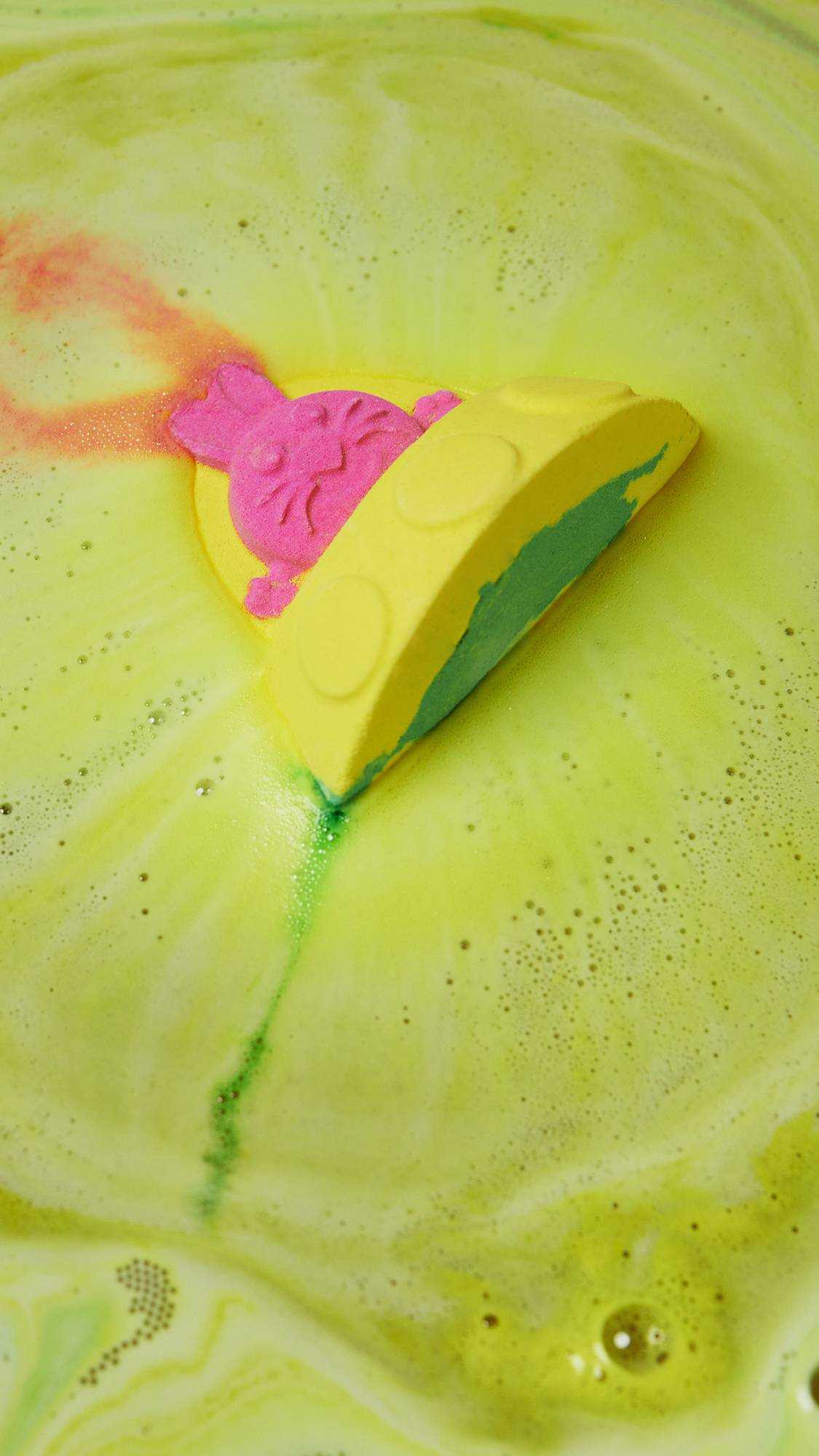 Alien Bunny Spaceship lays flay in the bath water shooting off foamy swirls of bright yellow and pink.