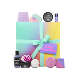 And Breathe. A large, square gift box wrapped in a delicately decorated colour gradient of teal, yellow, pink and orange, tied with a teal ribbon and gift tag. There are ten included Lush products surrounding the gift box. 