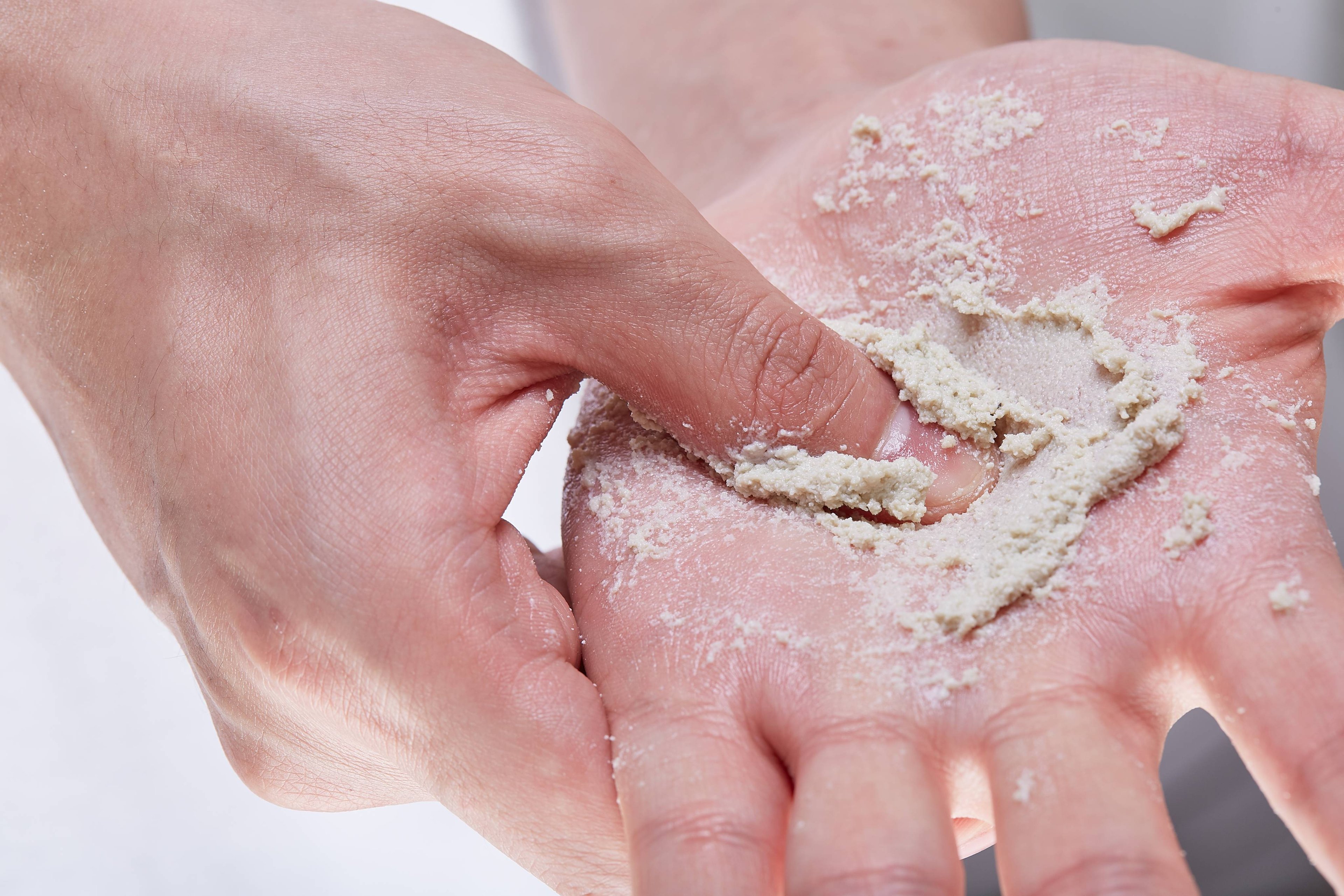 A close-up of model's hands shows Angels on Bare Skin cleanser mixed with water creating a luscious, cream paste.