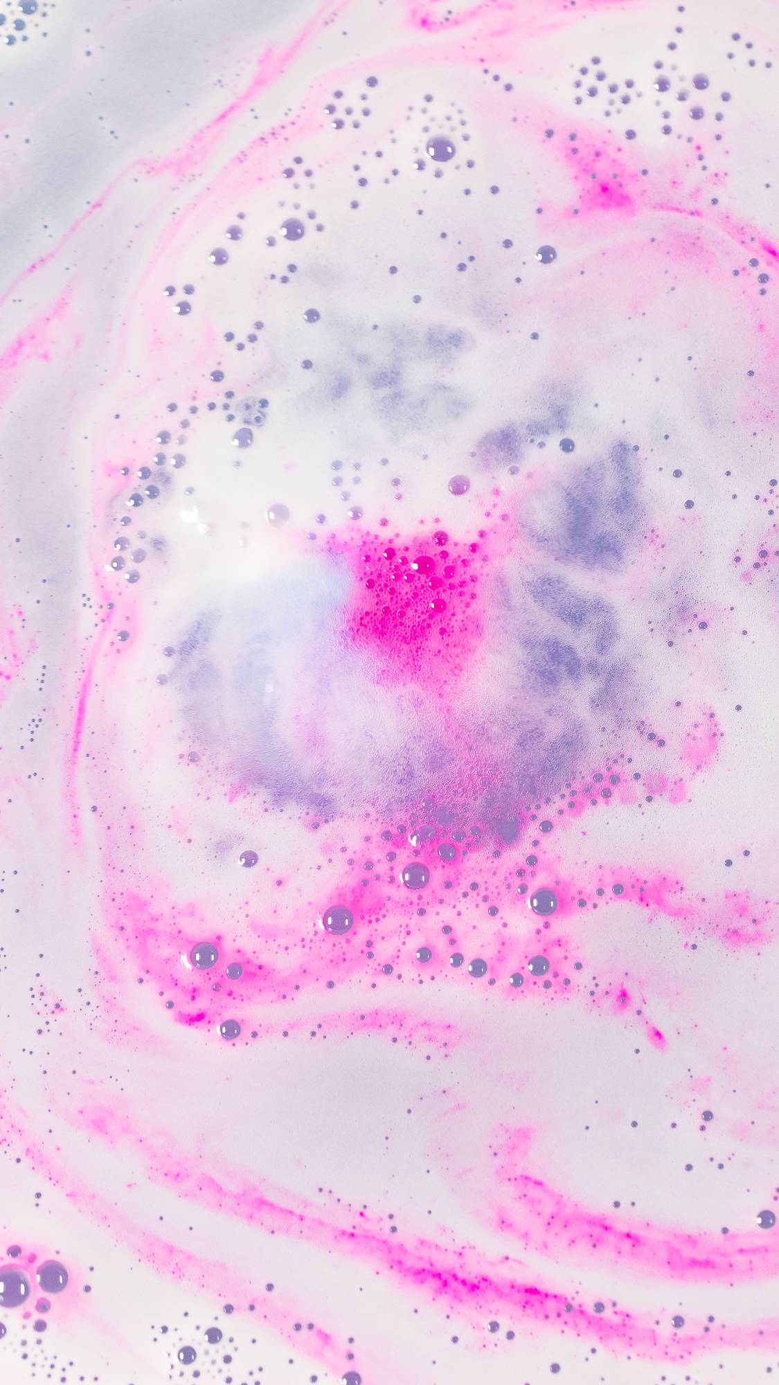 The Atom Heart Mother bath bomb has fully dissolved leaving foamy swirls of pink, blue and purple. 