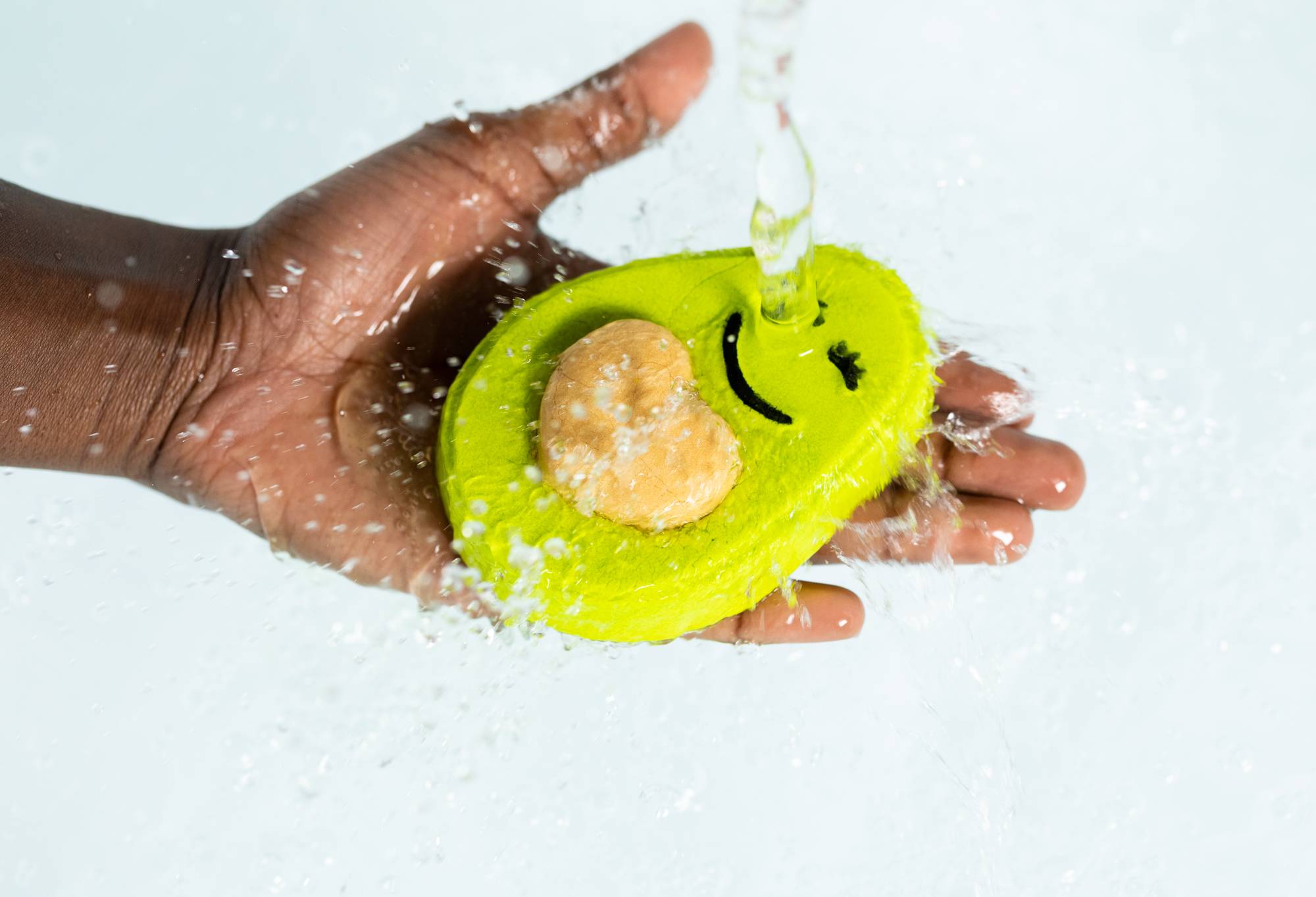Image shows the model's hand holding the Avo Cuddle bubble bar under running water. 