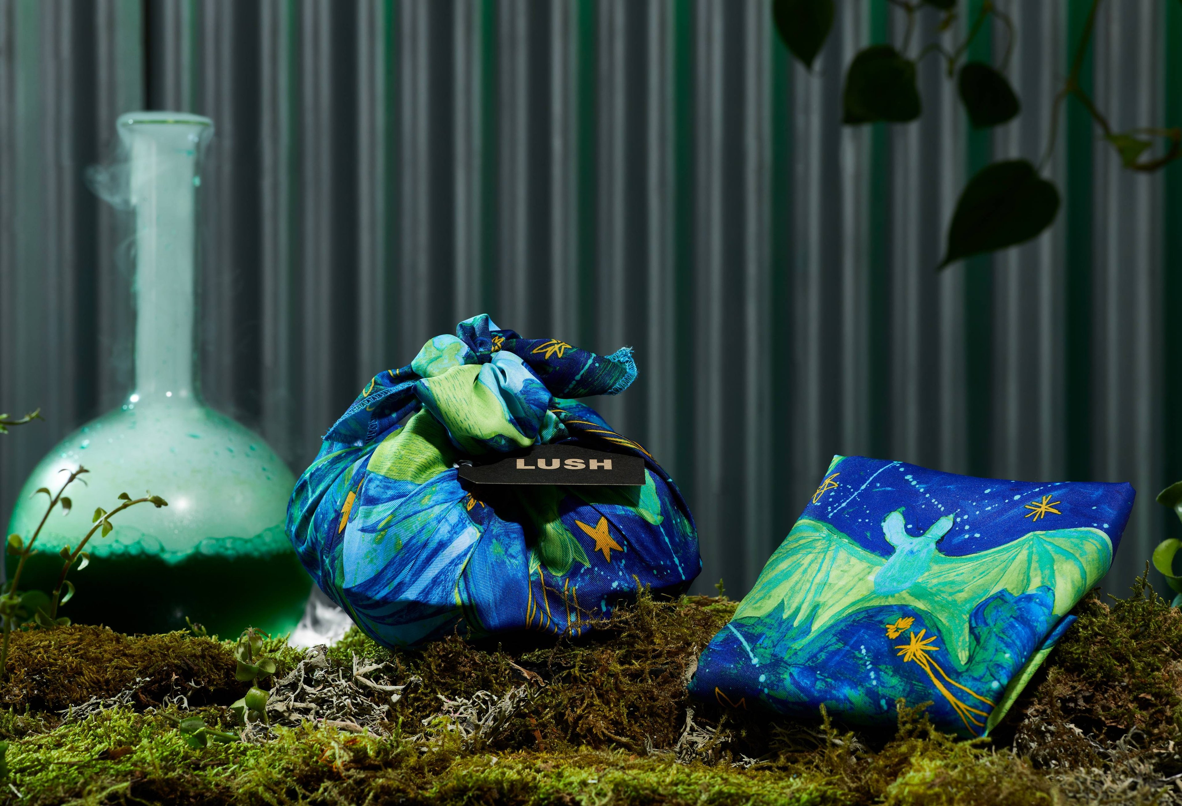 Bat Mates Knot Wrap, displayed in two separate ways in front of a dark green background, on a bed of moss. 