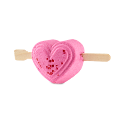 Be My Valentine. A bright pink, heart-shaped bubble bar with a wooden craft stick pierced through the centre like an arrow, and the front of the heart is decorated with a small cluster of tiny red hearts.