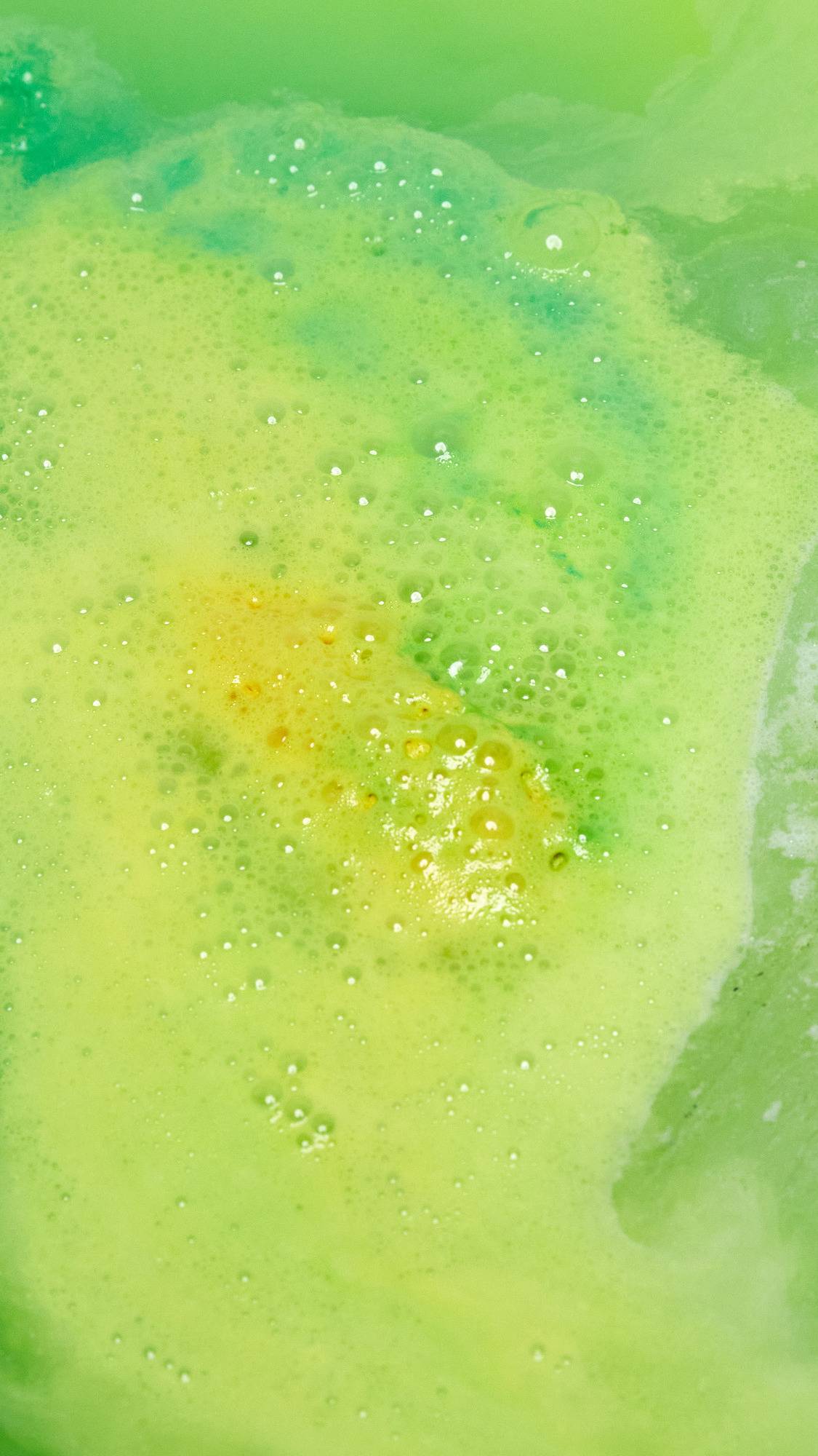 The Beat The Clock Badger bath bomb has fully dissolved leaving behind a thick blanket of lemon-lime, vibrant yellow and green foam. 