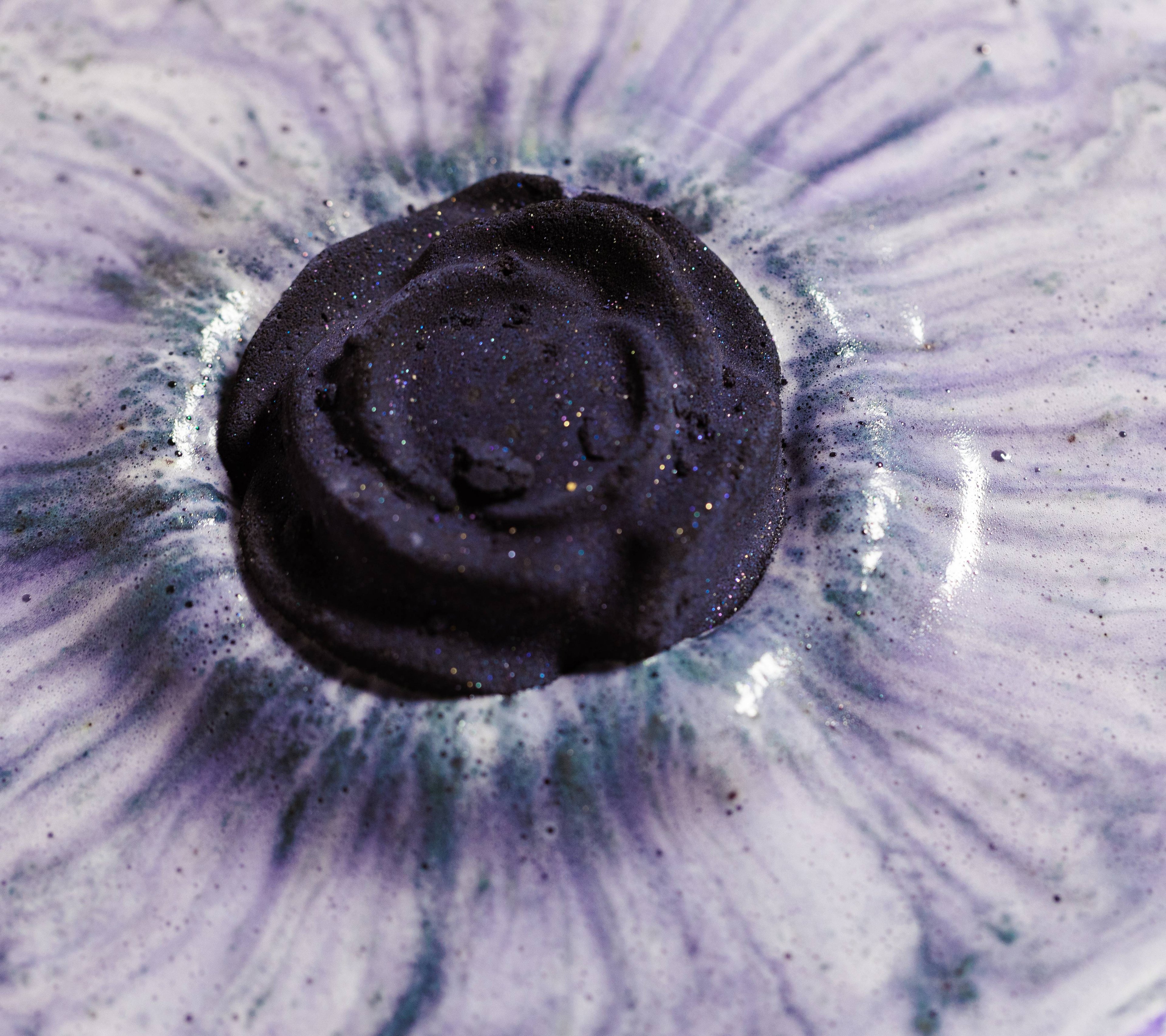 Back Rose bath bomb close-up of oozing, velvety purple and black thick foam.