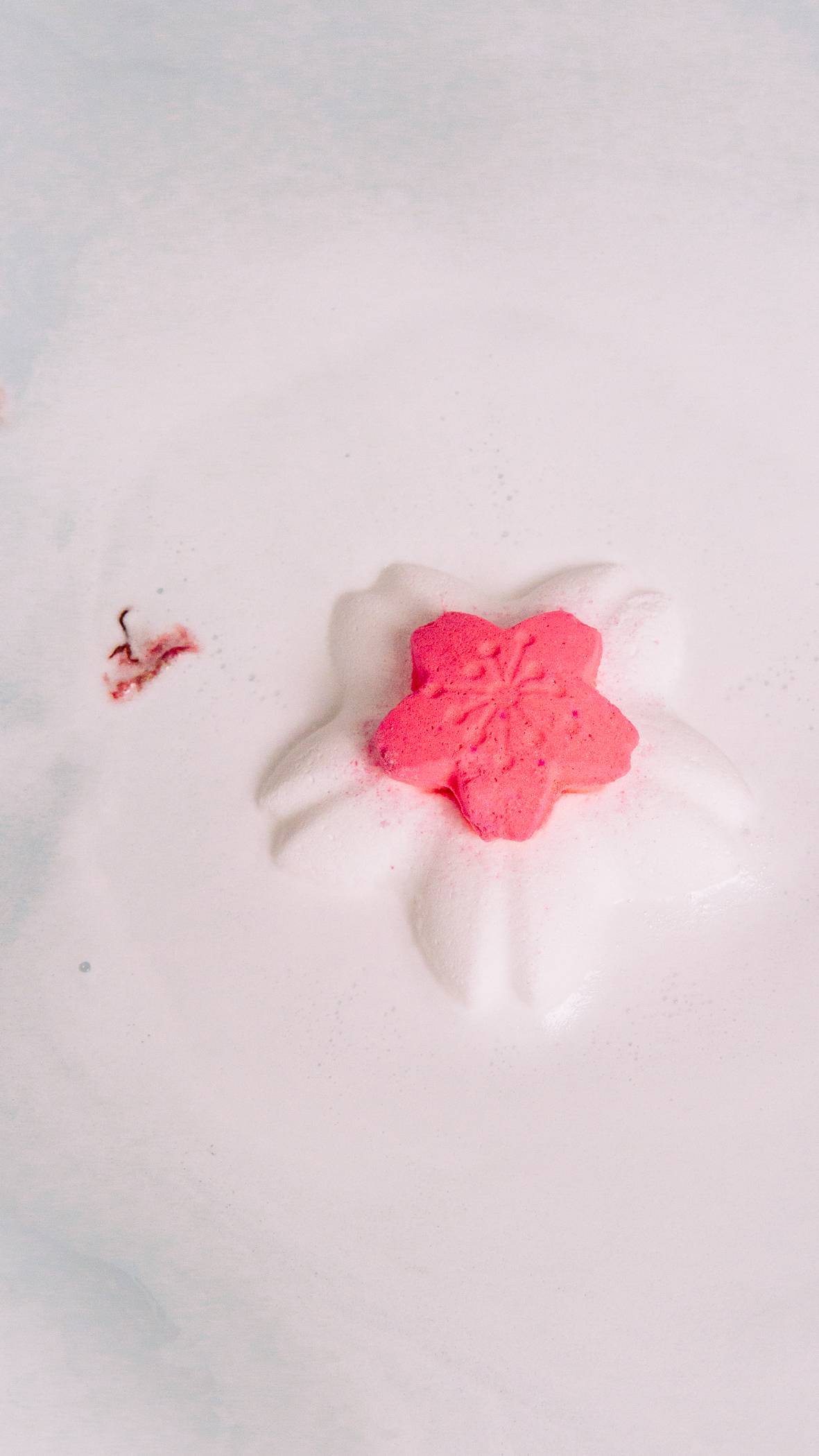 The Blooming Beautiful bath bomb is sitting on top of the bath water creating the past pink, velvety foam. 