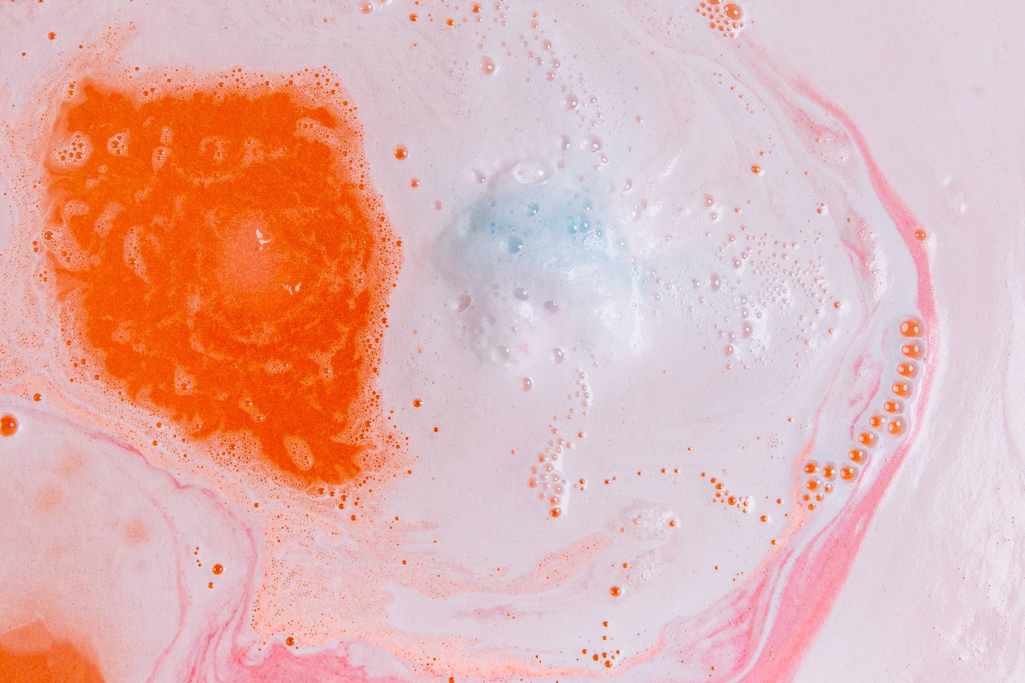 The image shows the bath surface blanketed in thick, velvety foamy swirls of pink white and orange. 