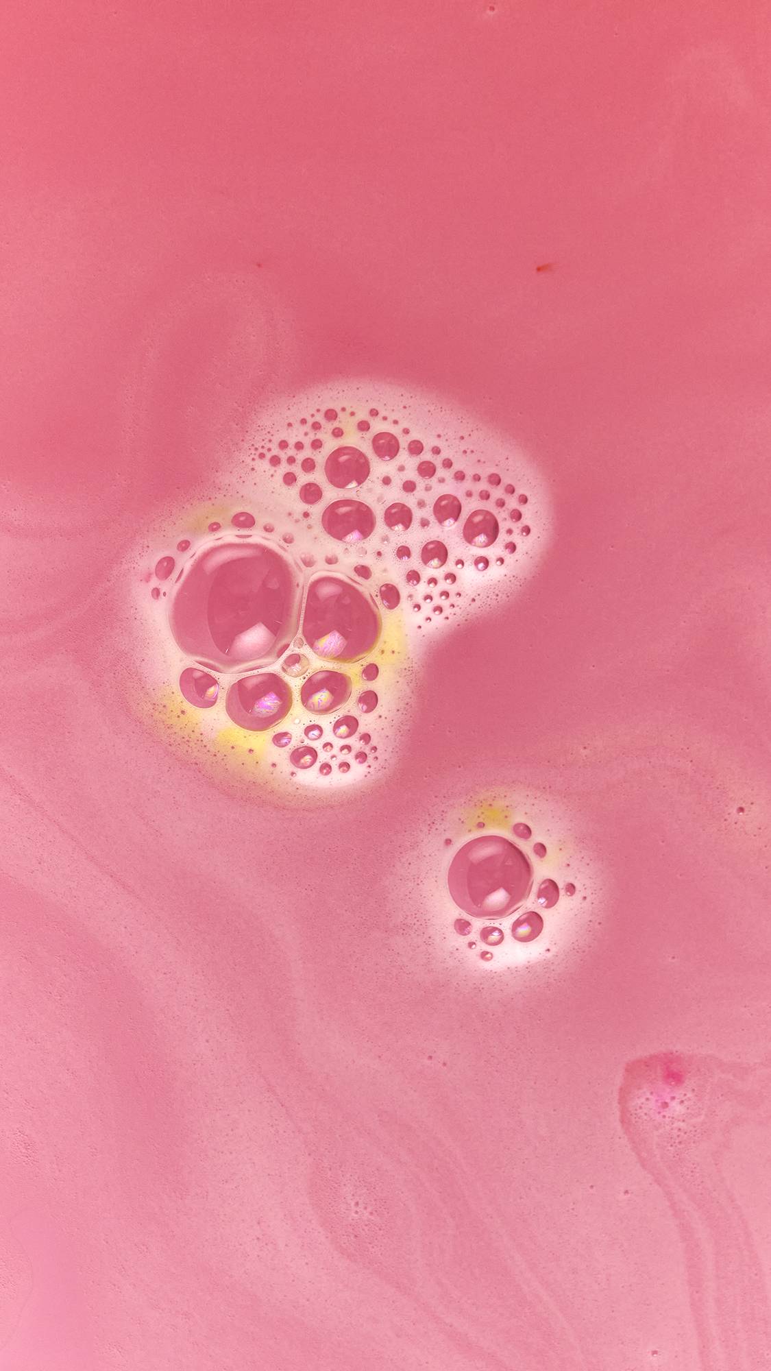 The image shows the delicate, velvet-pink water with gentle, foam bubbles and hints of yellow.