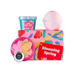 Blooming Spring gift. A wrapped, graphic pink box with a red "Blooming Spring" tag, a blue pot of blue body scrub, a pink bath bomb, a "Smitten" hand cream tin, and a pink soap with a gold butterfly.