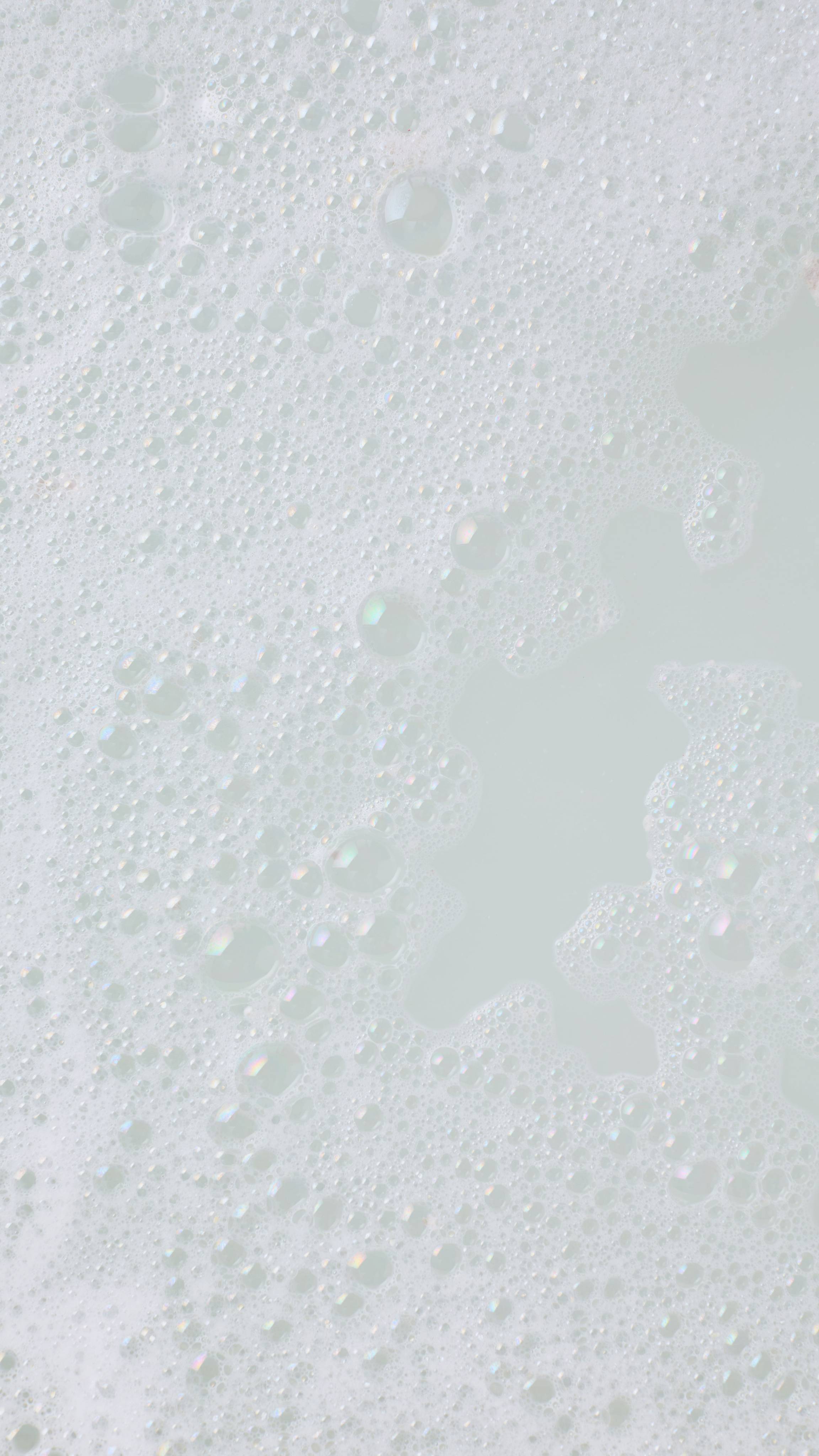 A close-up image of the bath water after using the Lush Christmas, Bubble Bear bubble bar. There is a blanket of thick, fat bubbles with creamy bath water visible below them. 
