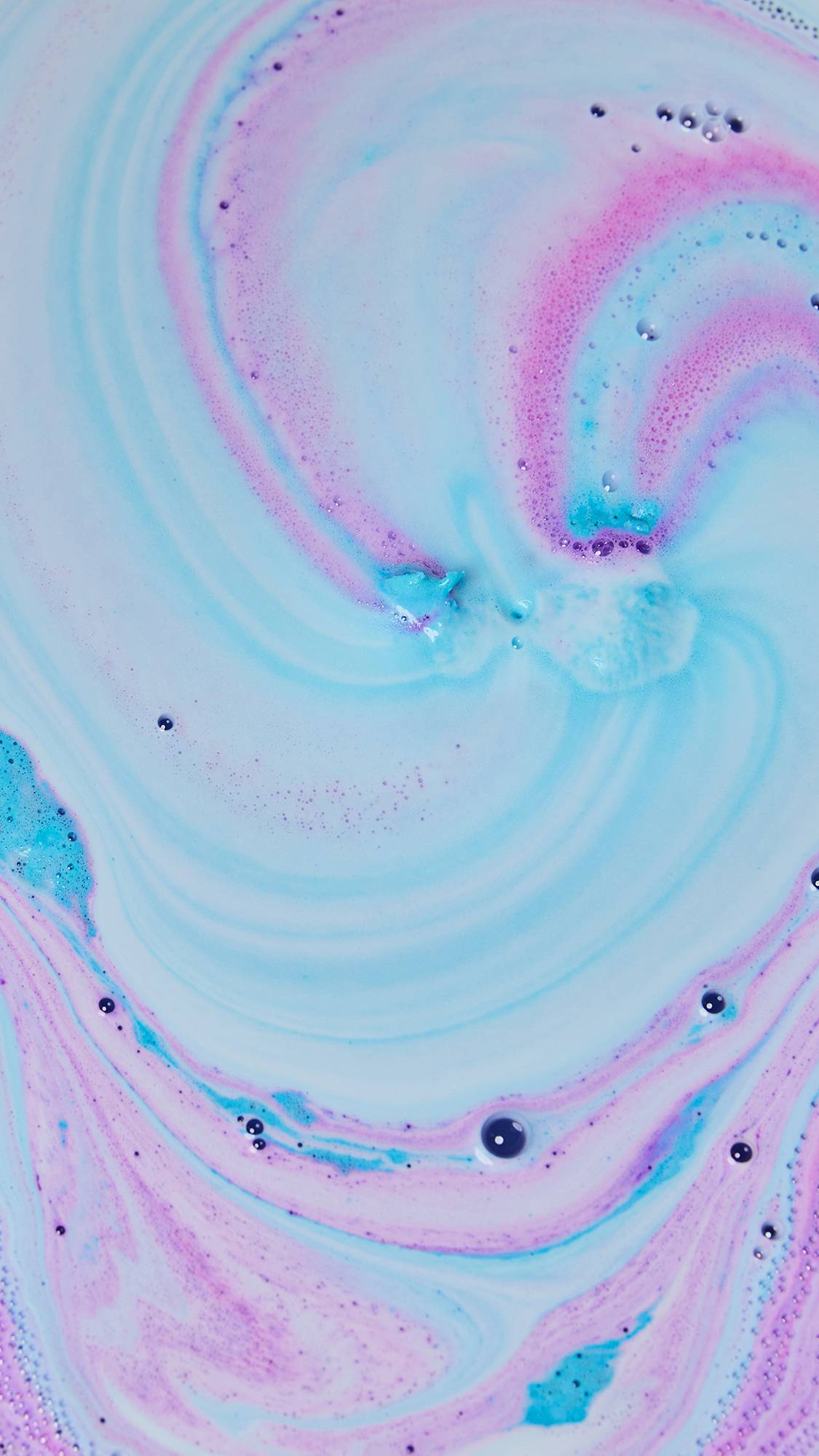 The Bunny Moon bath bomb has nearly fully dissolved leaving a galaxy of pink, blue and purple foamy ripples.
