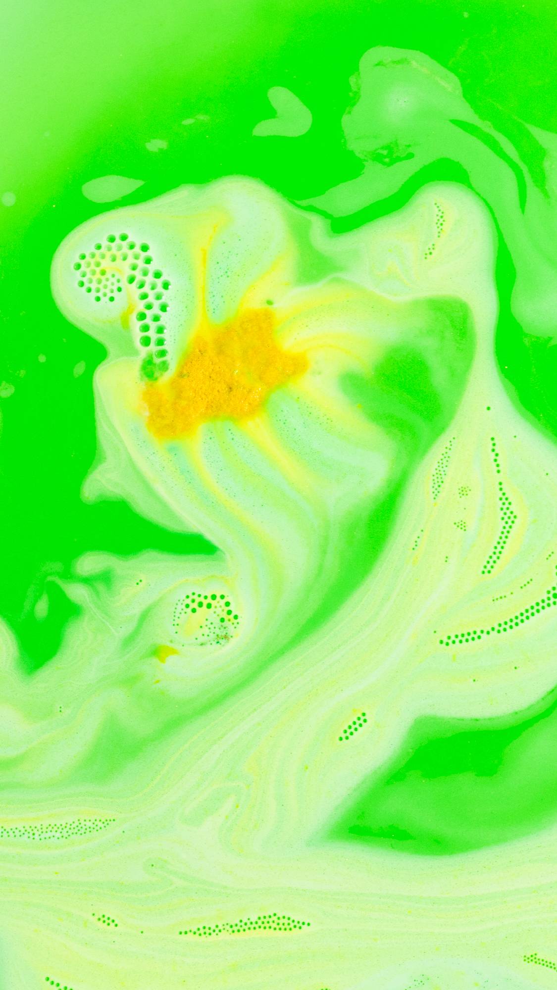 Catch Me If You Can bath bomb almost fully dissolved on a carpet of bright neon green and yellow foam.