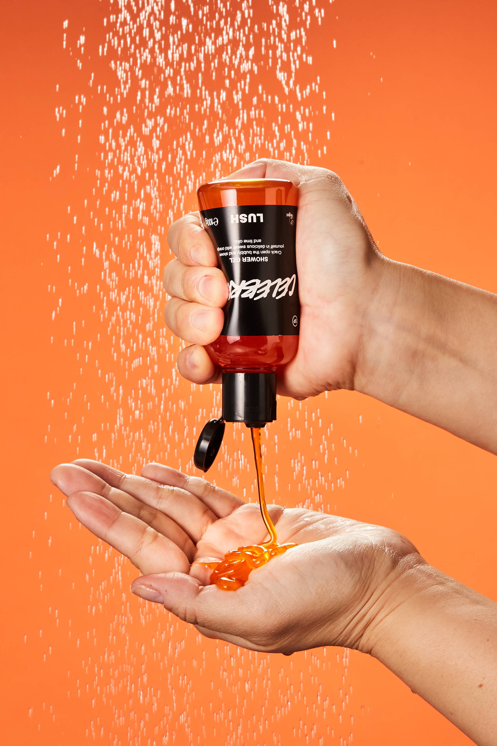 A close-up of the model's hand as they squeeze the Celebrate shower gel into their hand under running shower water.