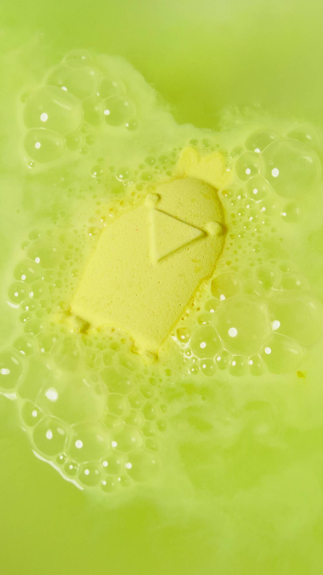 The Cheep Cheep bath bomb sits on top of the water fizzing bright, neon yellow foam.