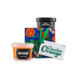 Chocolate Orange. A square gift box wrapped in blue paper with orange slice and star designs, wrapped in a green ribbon with a white gift tag. Two potted Lush products sit around the gift box.