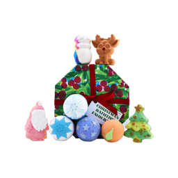 A Lush Christmas Bathtime Favourites gift set wrapped in festive holly paper with red ribbon, surrounded by eight bath products including a snowman, reindeer, Father Christmas, Christmas tree, and spherical bath bombs