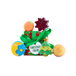 A Lush Christmas Cheer! gift box tied with a green ribbon, displayed alongside five bath products, including a crescent moon and star-shaped bubble bar, a Christmas tree, and round bath bombs