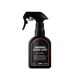 A matte black Lush body spray bottle with a trigger nozzle and a terracotta-bordered label reading 'Cinnamon Spiced Latte', set against a plain white background.