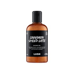 A clear bottle filled with shimmering, bronze-orange Lush Cinnamon Spiced Latte shower gel, topped with a black cap and featuring a black label