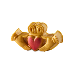 Claddagh. A St. Patrick's Day-themed soap shaped like the traditional Irish Claddagh. The soap is a golden-caramel colour with golden lustre throughout and shaped like two hands reaching in to hold a red heart with a crown on top.
