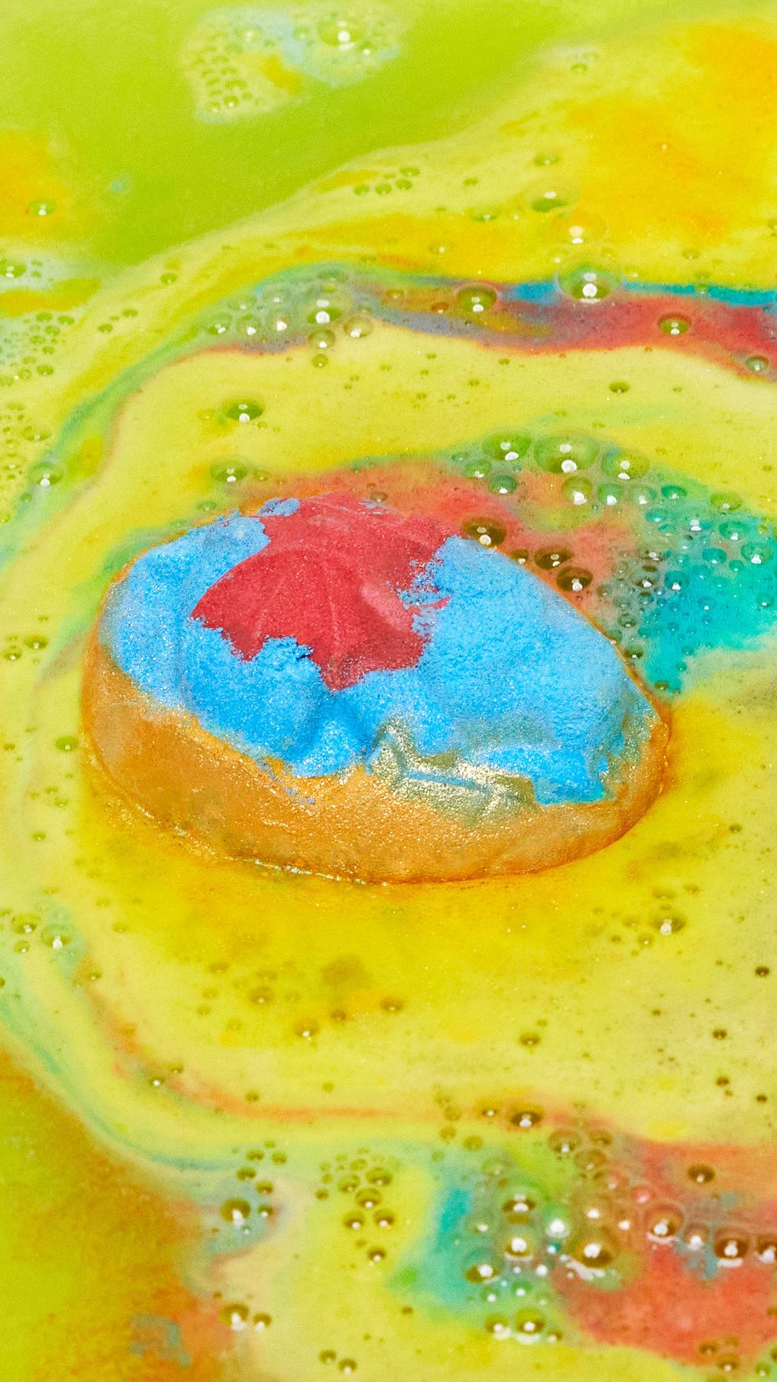 The Crackle bath bomb has just been gently placed into the bath and is beginning to give of a sea of bright yellow, shimmering waters with blue and red ripples. 