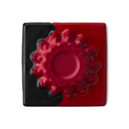 A square, two-toned block of "Crimson Reds" Lipstrick Square with opaque black and vibrant red sections. The red side features a raised circular, gear-like texture.