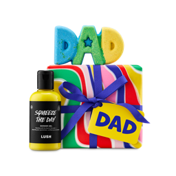 DAD gift. A vibrant Lush gift set featuring a colourful swirl-patterned gift box with a blue ribbon and "DAD" tag, and a blue, green, and yellow "DAD" shaped bath bomb on top and "Squeeze The Day" shower gel to the side. 