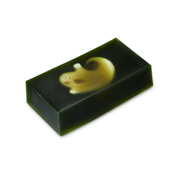 Demon in the Dark. The image shows a thick, rectangular slab of dark, translucent green soap. Embedded near the top is a white, ghost-shaped soap visible beneath just the surface. 