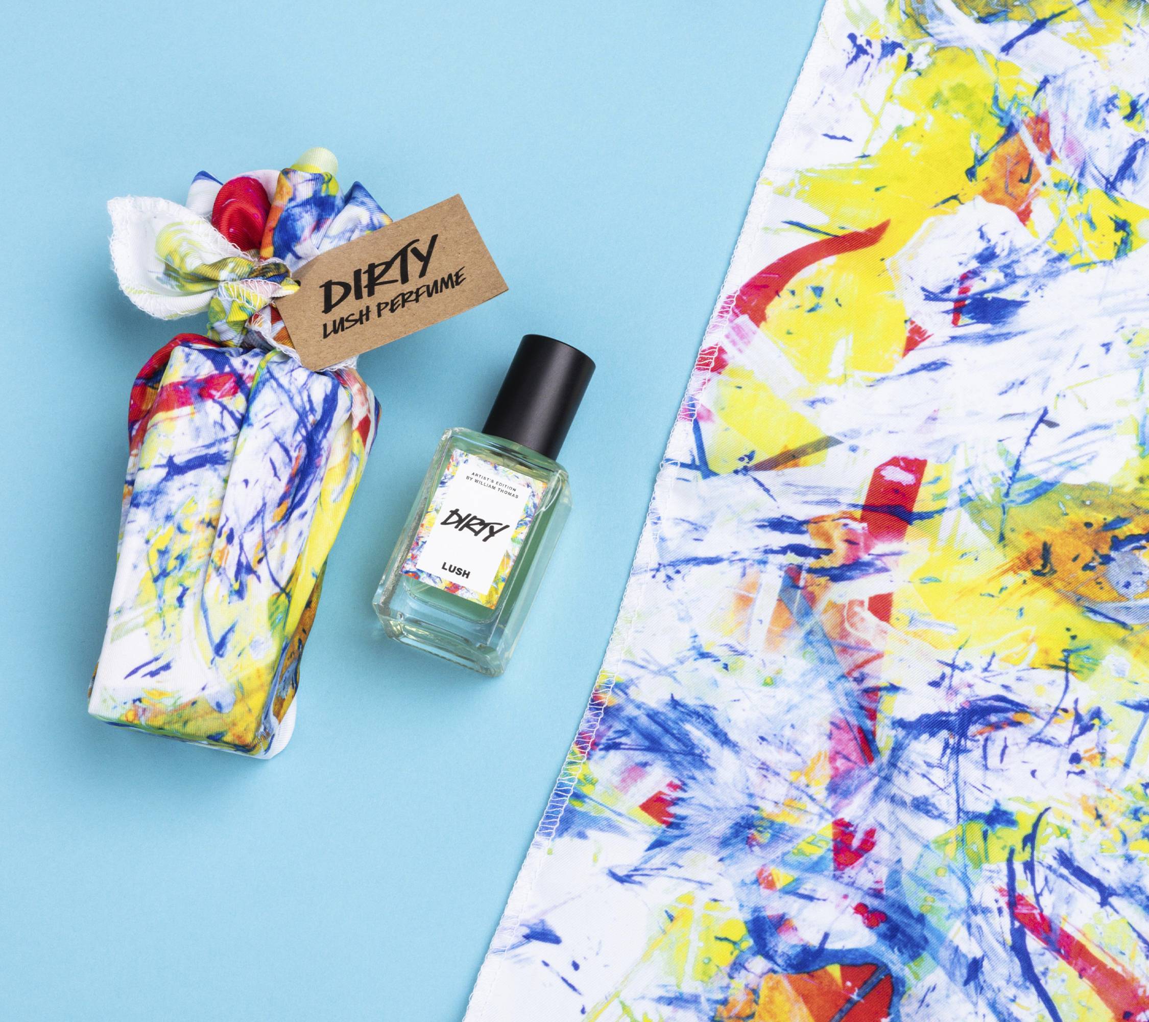 Dirty lies on a light blue background, alongside its two elements: a small bottle of Dirty perfume and a colourful knot wrap.