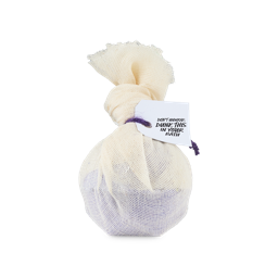 Dreamy Oaty Lavender Cataplasm.  A purple, spherical bath bomb wrapped in muslin fabric, tied with a knot and purple string and product tag which reads "Don't unwrap, dunk this in your bath"
