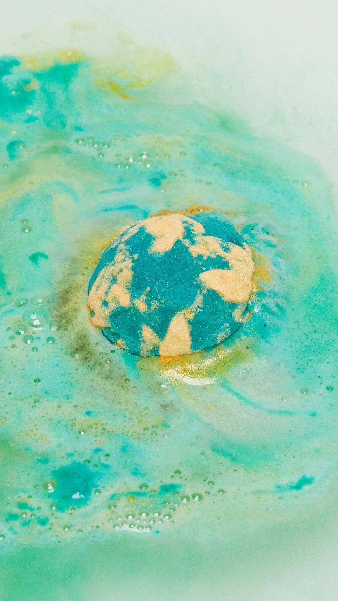 The Druid of Bath bath bomb has just been placed on the bath water as it pushes out a deep green foam with flecks of golden swirls throughout. 