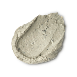 Earthy, Woody, Karma. A thick, textured dollop of pale beige foot mask. The product has a dense, matte consistency with visible dark exfoliating flecks and small lumps, showing a swirled and slightly peaked surface.